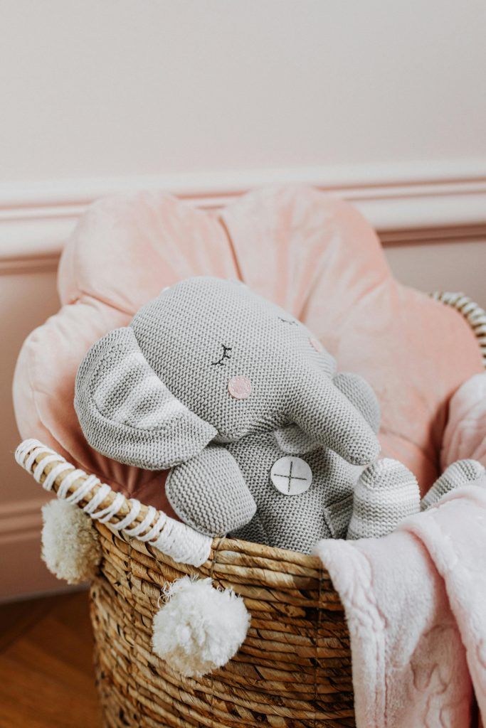 pexels-photo-4886916-4886916 Adorable stuffed elephant toy nestled in a soft woven basket with pink lining.